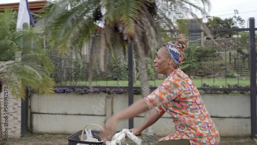 video de una hermosa mujer morena con cabello afro y una pañoleta en su cabeza, muy sonriente vendiendo sus productos mientras se transporta en una bicicleta photo