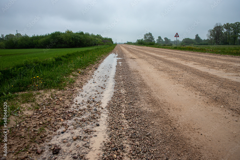 Naklejka premium road in Latvia countryside. Zemgale flat landscape with fields and forest trees. Road from Jelgava town to Stalgene village