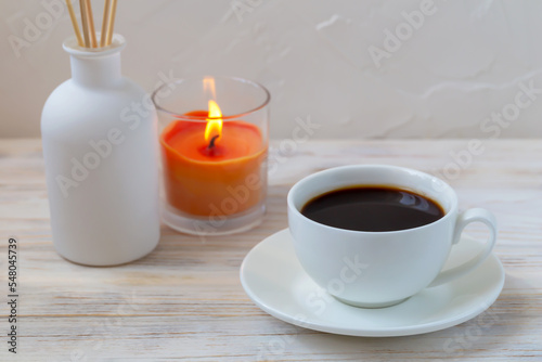 Cup of coffee, aroma reed diffuser and candle
