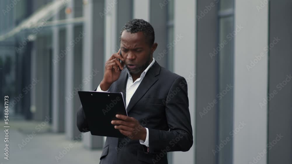 Middle aged african american man manager talking on phone with partners, discussing business plan, empty space Middle aged african american man manager talking on phone with partners, discussing business plan, empty space