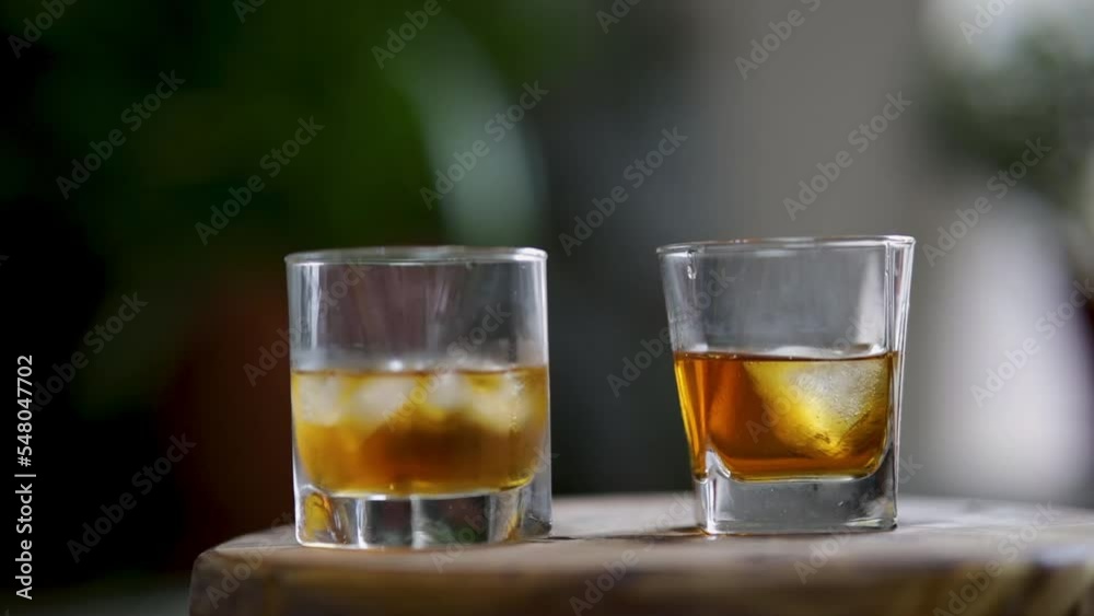 Pouring whiskey, cognac into glass. Whiskey and ice in a glass.
