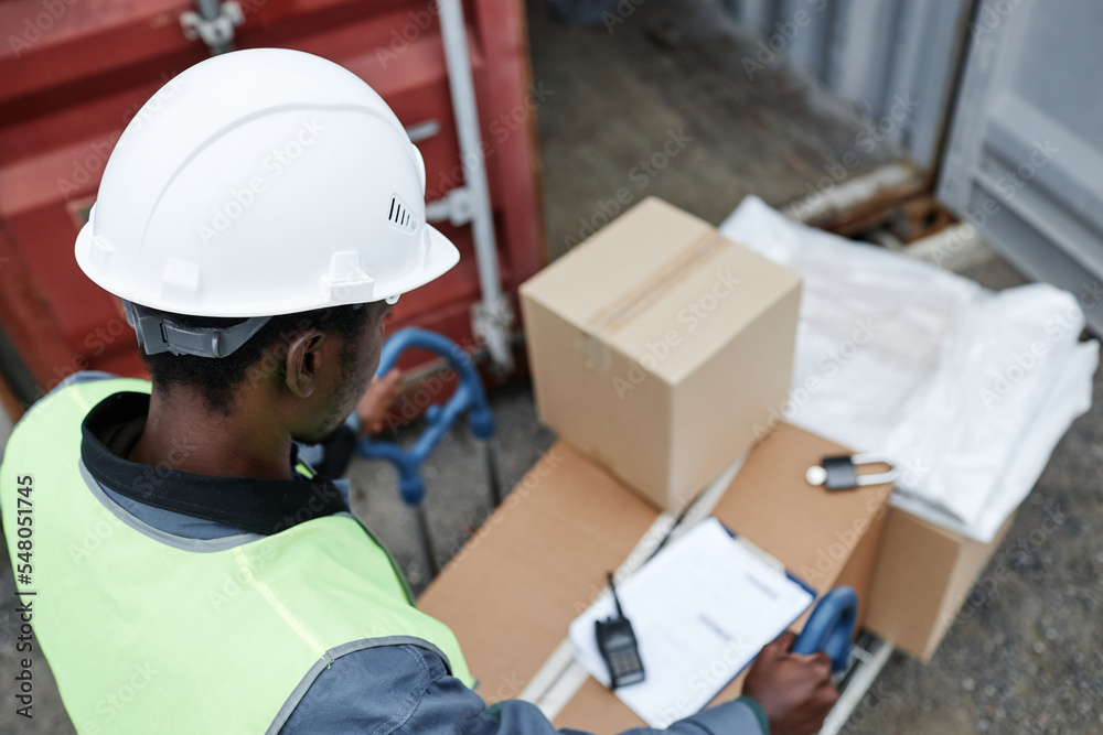 Top view at worker pushing cart with boxes at shipping docks, copy space Top view at worker pushing cart with boxes at shipping docks, copy space