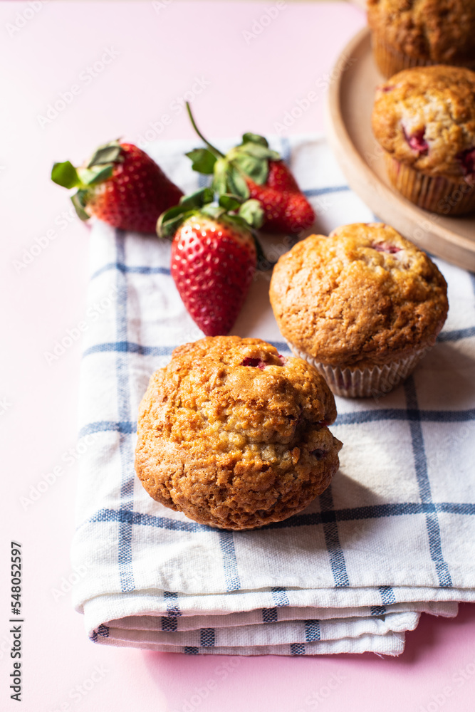 Strawberry muffins on a napkin on a pink background. Close up. Strawberry muffins on a napkin on a pink background. Close up.