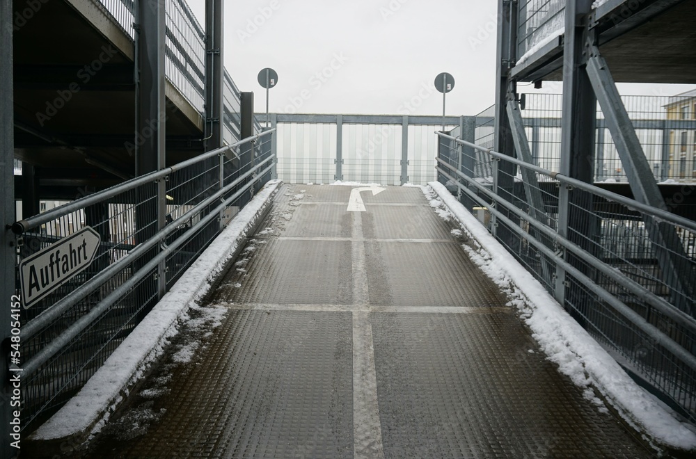 Nasse Auffahrt im Parkhaus bei Schnee und grauem Himmel am Morgen im Winter Nasse Auffahrt im Parkhaus bei Schnee und grauem Himmel am Morgen im Winter