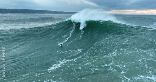 Aerial view of a professional big wave surfer on a big wave in Nazare surfing spot, Portugal. Jet ski surfing in Atlantic ocean.