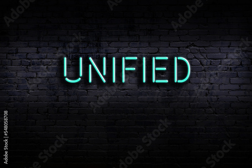 Neon sign. Word unified against brick wall. Night view photo