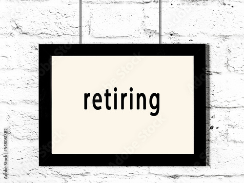 Black frame hanging on white brick wall with inscription retiring