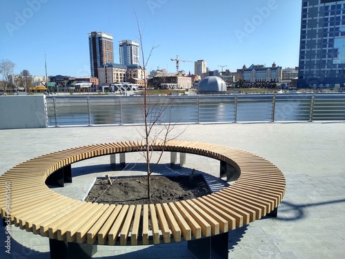 Fotografia Round wooden bench in the city park on the embankment line