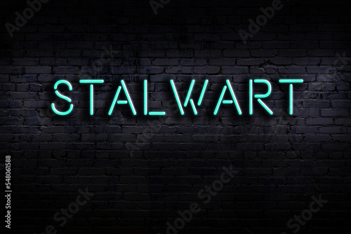 Neon sign. Word stalwart against brick wall. Night view