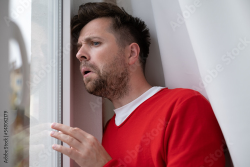 Caucasian man peeking through window being shocked with accident on street photo