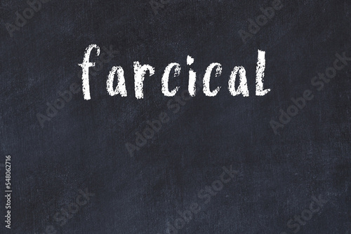 College chalk desk with the word farcical written on in