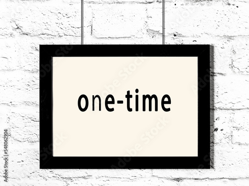 Black frame hanging on white brick wall with inscription one-time