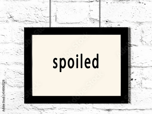 Black frame hanging on white brick wall with inscription spoiled photo