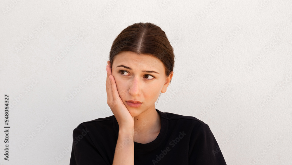 Portrait of pensive young woman looking away on white background. Caucasian woman wearing black T-shirt posing with doubtful expression. Uncertainty and doubt Portrait of pensive young woman looking away on white background. Caucasian woman wearing black T-shirt posing with doubtful expression. Uncertainty and doubt