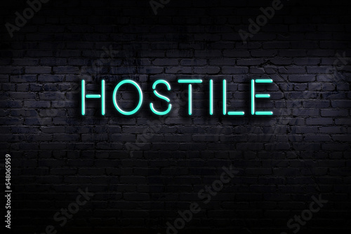 Fotografija Night view of neon sign on brick wall with inscription hostile