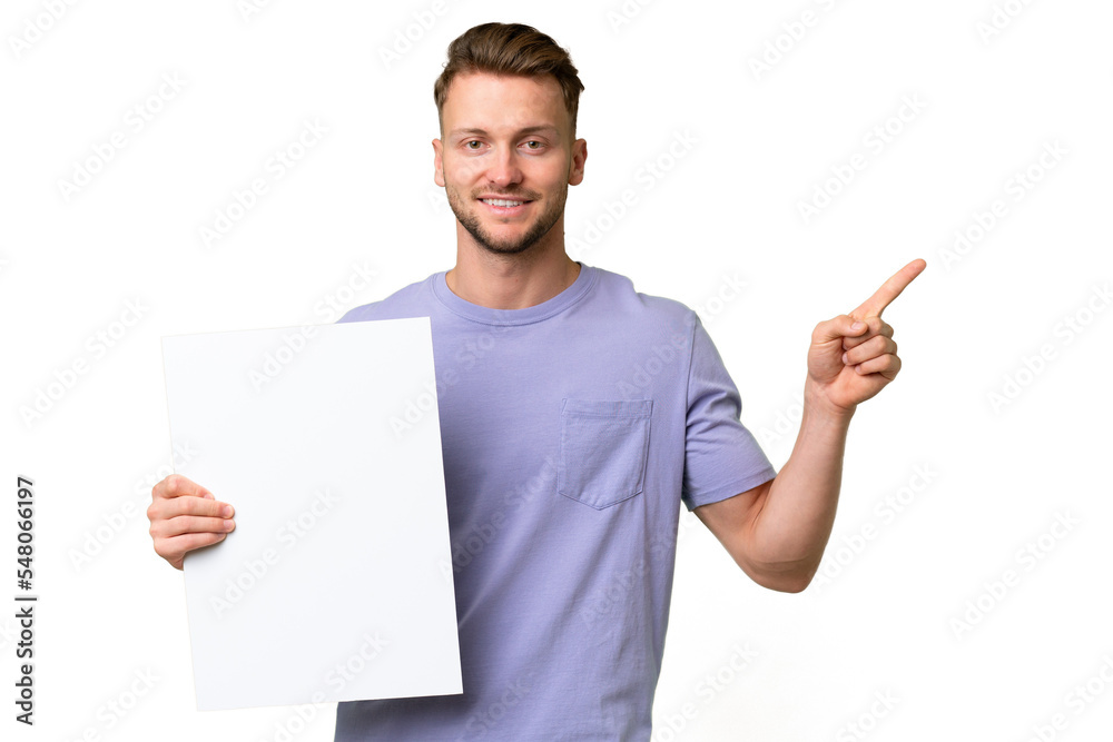 Young blonde caucasian man over isolated background holding an empty placard and pointing side Young blonde caucasian man over isolated background holding an empty placard and pointing side