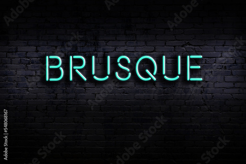 Neon sign. Word brusque against brick wall. Night view photo