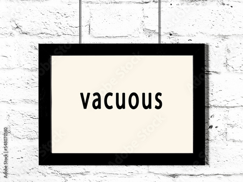 Black frame hanging on white brick wall with inscription vacuous