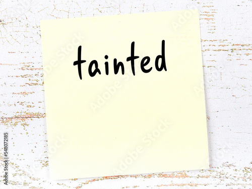 Canvas Print Yellow sticky note on wooden wall with handwritten word tainted