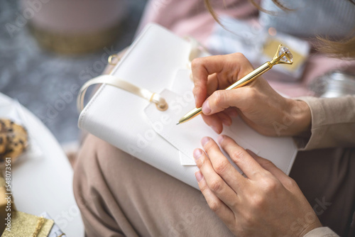 Closeup female hands writing Christmas festive congratulations on card for gift box package