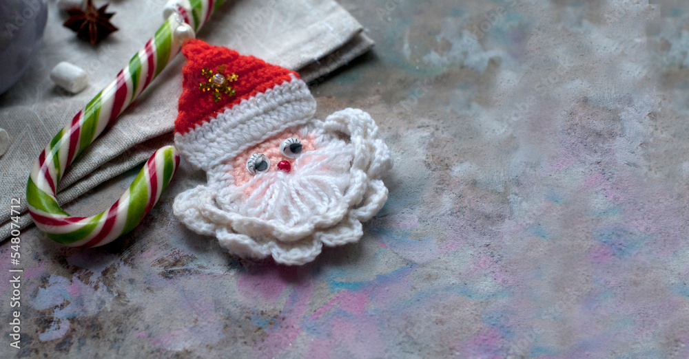 New Year and Christmas card with handmade knitted Santa Claus. Card with Christmas decoration on gray background. Top view. Space for text