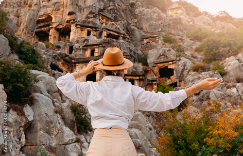 Foto Back view, happy woman tourist archaeologist in hat background old tomb Myra Anc