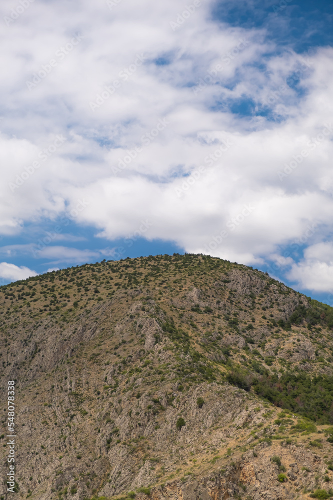 high rocky mountain landscape in the cloudy blue sky