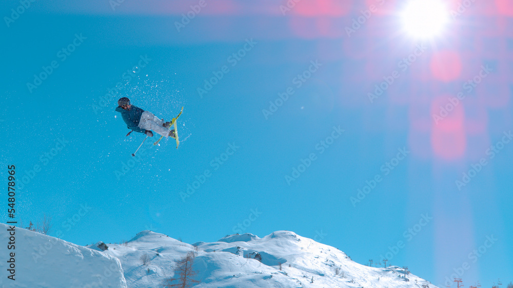 LOW ANGLE VIEW Male skier jumping big air kicker at snow park in snowy ski area
