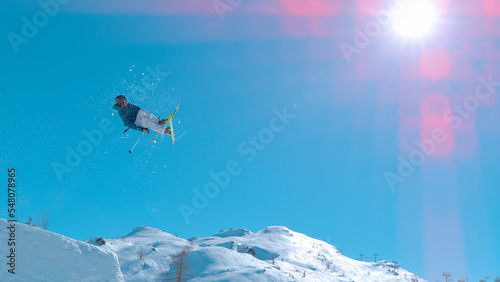 LOW ANGLE VIEW Male skier jumping big air kicker at snow park in snowy ski area © helivideo