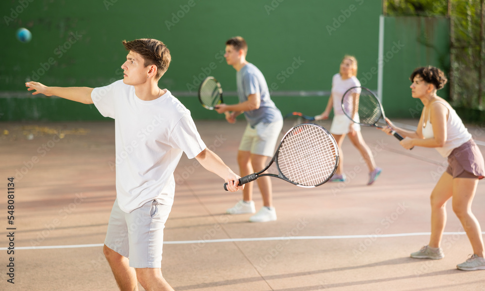 Young male sportsman preparing to hit ball with racket. Frontenis game on outdoor court