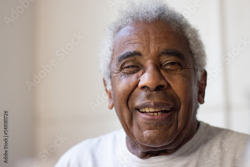 Close-up of elderly mans face. Happy African American man with grey and curly hair smiling and looking at camera with joy. Happy life and taking care of elderly people concept