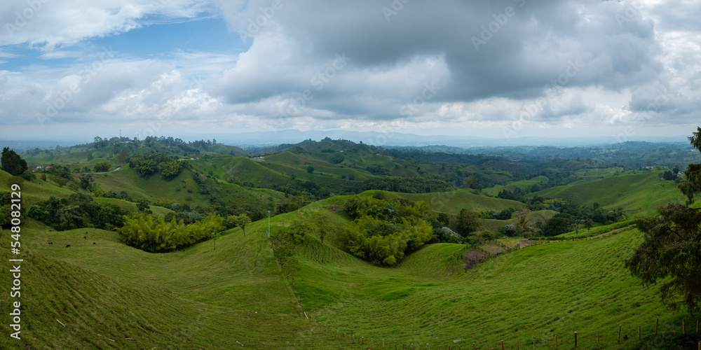 Green Mountains Surrounded by Trees and Crops on a Slightly Cloudy Day in the Morning