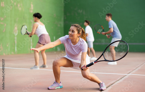 Latin woman playing frontenis on outdoor pelota court during training. Woman playing Basque pelota speciality. © JackF