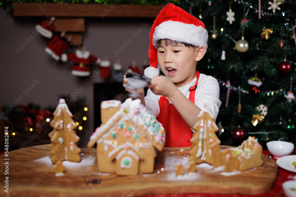 young girl wearing Santa hat was decorating gingerbread house for celebrating Christmas at home