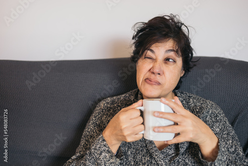Vászonkép Early morning woman holding a cup of hot coffee, tired and with an expression of disgust for the monotony, grimace and amused face