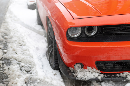 Headlights and soot of a red sports car on the snow. Beautiful Muscle car in the snow