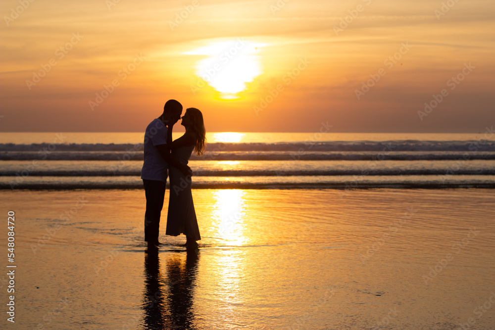 Gentle family walking on beach at sundown. Man and woman in casual clothes strolling near water at dusk. Love, family, nature concept