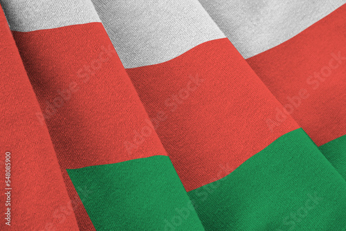 Oman flag with big folds waving close up under the studio light indoors. The official symbols and colors in banner photo