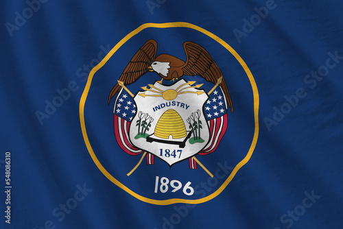 Utah US state flag with big folds waving close up under the studio light indoors. The official symbols and colors in banner photo