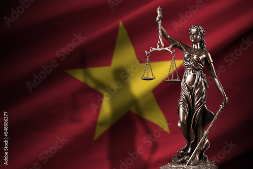 Vietnam flag with statue of lady justice and judicial scales in dark room. Concept of judgement and punishment