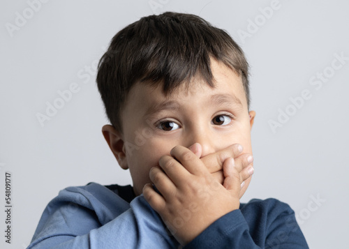 Male boy about 4 years old expressing emotions with his hands on his face