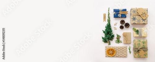 Eco friendly Christmas composition with gift boxes in craft reusable paper and natural decor on white background top view. Zero waste environmentally friendly Christmas concept.