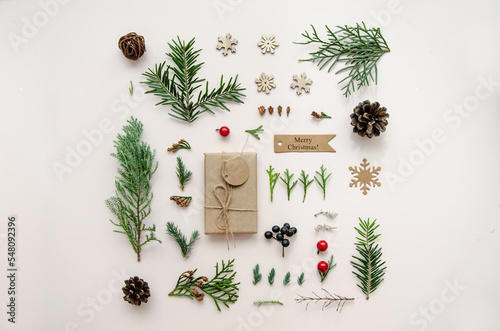 Christmas composition. Gift, fir tree, pine tree, cypress branches and cones, decorations on white background. Christmas, winter, new year concept. Flat lay, top view, copy space.