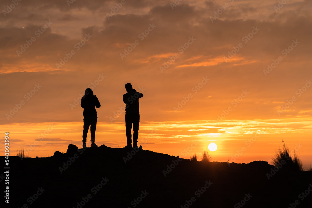 Couple looking at the horizon, silhouette of a beautiful sunset