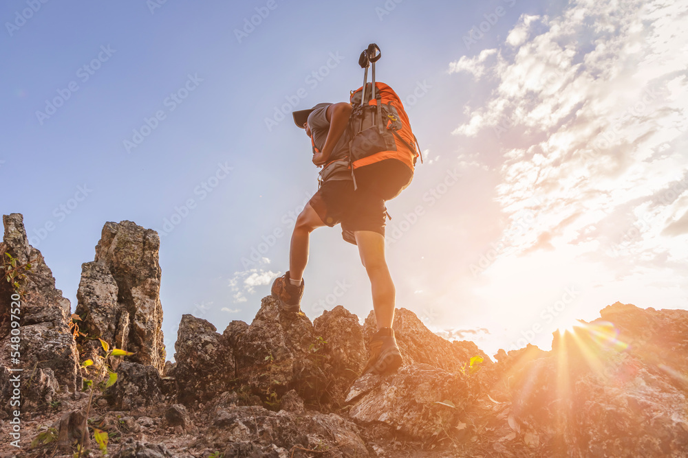 Male hiker with backpack walking on top rock mountain landscape and beautiful view sunset background.Hiker men's hiking living healthy active lifestyle.