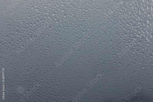 Window glass with water drops on light grey background, closeup