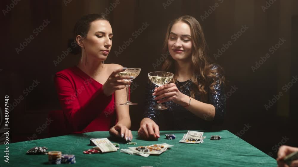 young women stare at their poker playing cards, make bets while playing in the casino. Entertainment industry and luxury lifestyle. The concept of gambling in the casino and poker. young women stare at their poker playing cards, make bets while playing in the casino. Entertainment industry and luxury lifestyle. The concept of gambling in the casino and poker.
