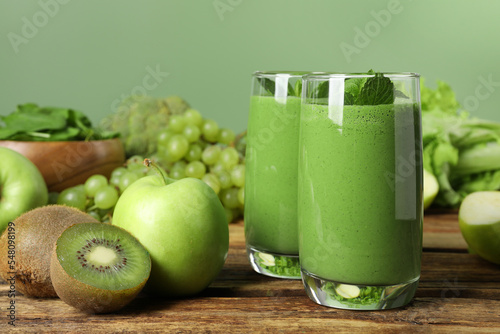Green smoothie in glasses and fresh ingredients on wooden table