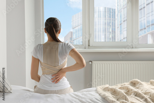Fotografía Woman with orthopedic corset sitting in bedroom, back view