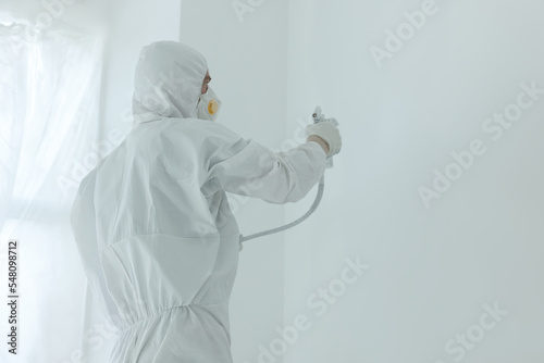 Decorator painting wall with spray, space for text